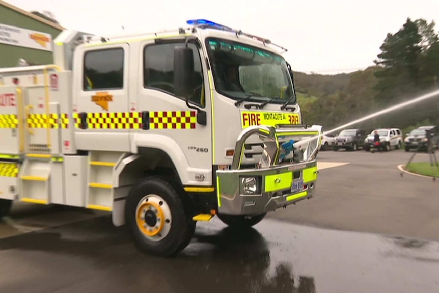 A white fire truck spraying water from its front.