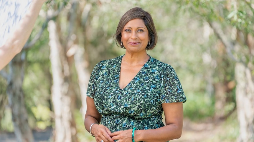 Indira Naidoo stands with a blurred out Australian bush behind her.