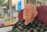 Elderly man sitting on an arm chair.