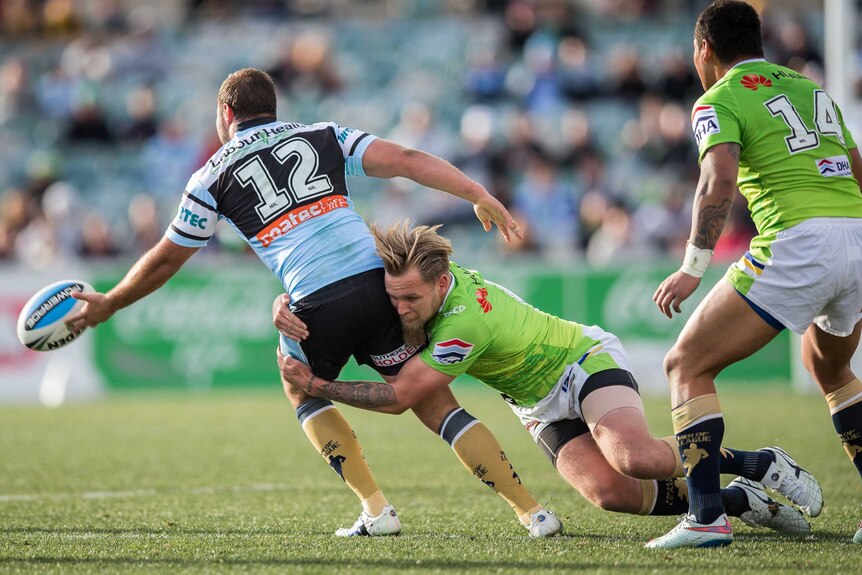 Wade Graham of the Cronulla-Sutherland Sharks is tackled by Blake Austin