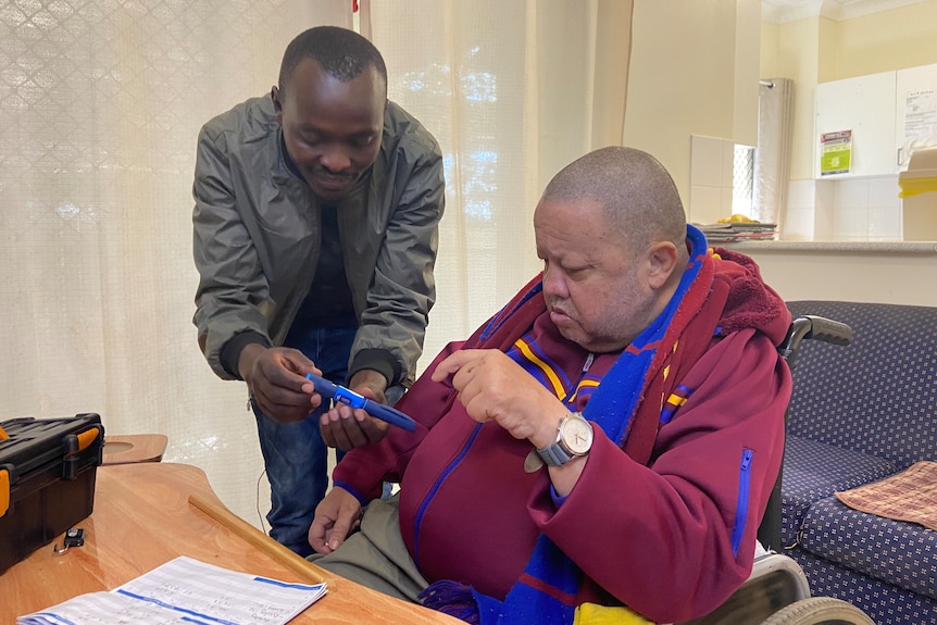 Silvanus Kimutai demonstrating diabetic tool to home care client Robert Borey