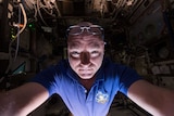 A NASA astronaut looks into the camera in a selfie in the International Space Station