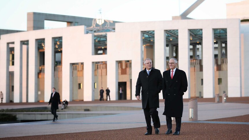 Scott Morrison and Malcolm Turnbull walk down a slope away from Parliament House. They are wearing warm coats