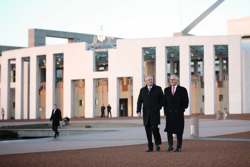 Scott Morrison and Malcolm Turnbull walk down a slope away from Parliament House. They are wearing warm coats