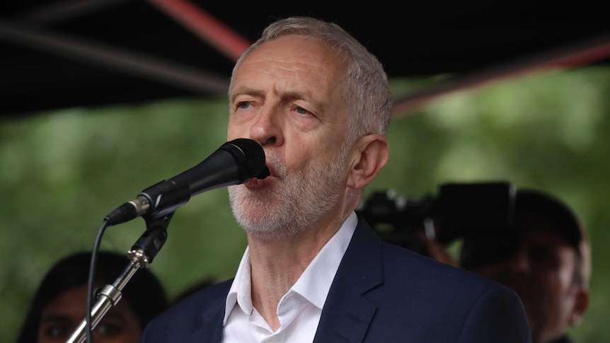 Britain's opposition Labour party leader Jeremy Corbyn speaks into a microphone.