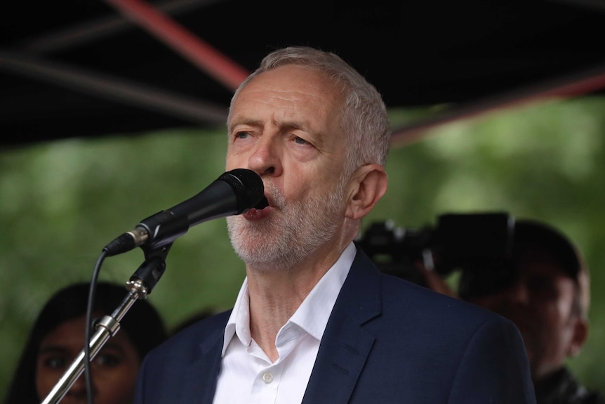 Britain's opposition Labour party leader Jeremy Corbyn speaks into a microphone.