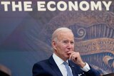 President Joe Biden listens in front of a sign on the wall that reads "the economy" during a meeting with CEOs.