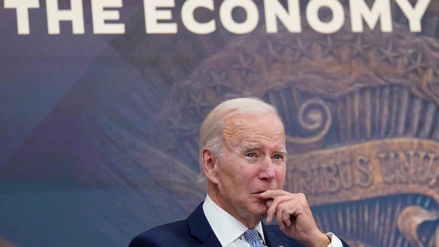 President Joe Biden listens in front of a sign on the wall that reads "the economy" during a meeting with CEOs.