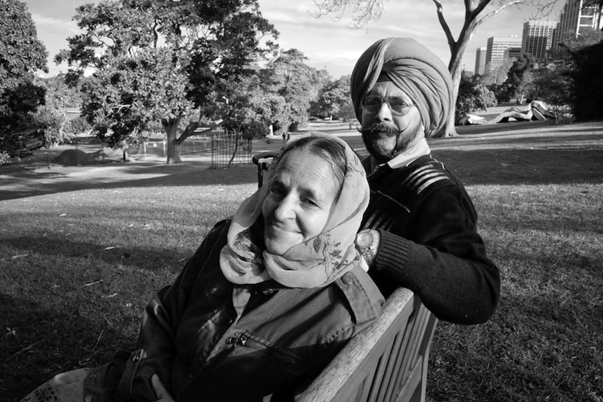 A Sikh man and a woman sitting on a park bench at Sydney's Royal Botanic Gardens.