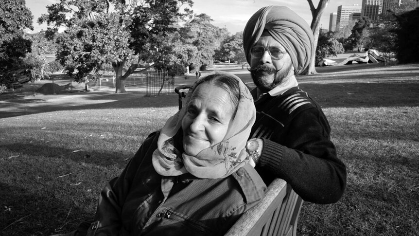 A Sikh man and a woman sitting on a park bench at Sydney's Royal Botanic Gardens.