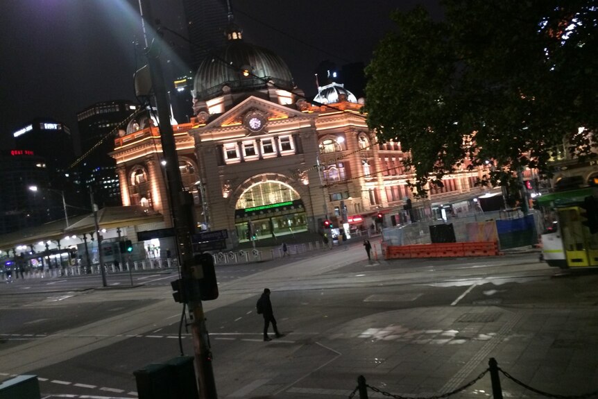 Flinders St stations building with single person crossing the road.