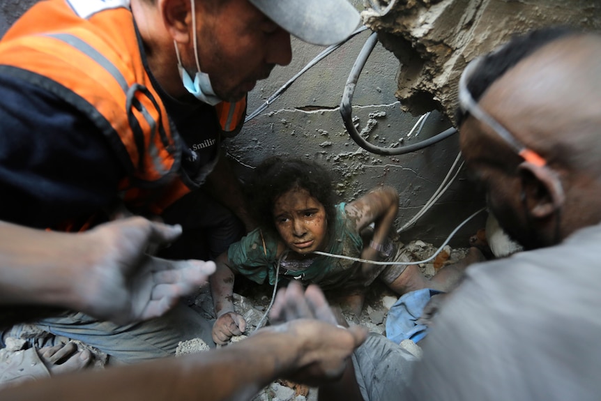 Men attempt to pull a girl out from beneath rubble. 
