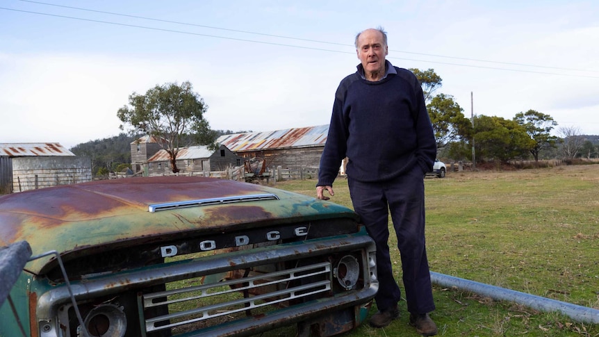 Picture of a man standing next to a rusty car part which says 'Dodge'