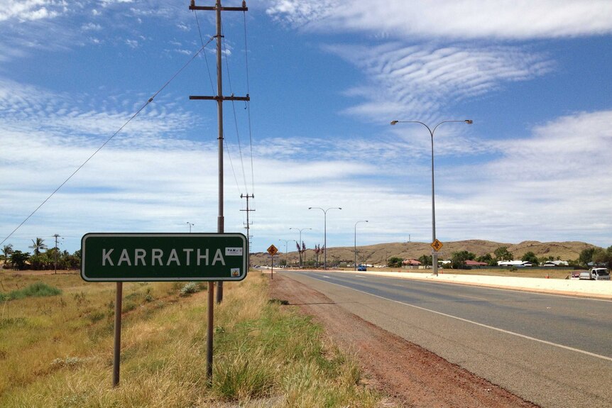 A road sign for Karratha beside an empty bitumen road