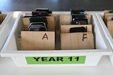mobile phones belonging to students are in a tray after the school banned them during school hours