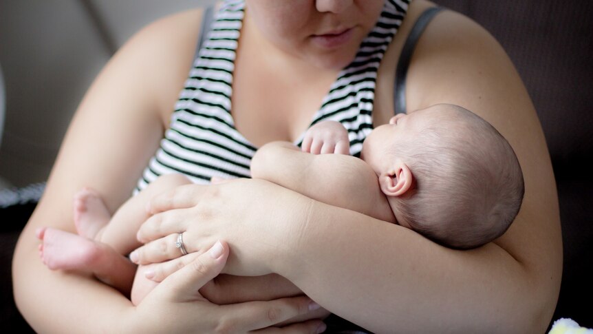 Women cradles baby in her arms.