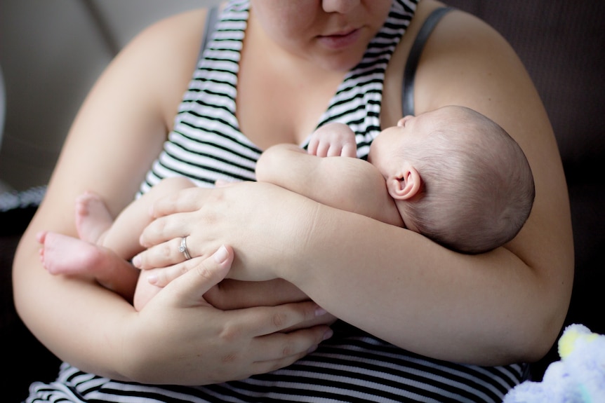 Women cradles baby in her arms.