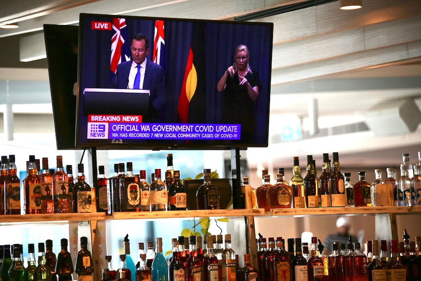 Una conferencia de prensa de Mark McGowan COVID-19 se reproduce en una pantalla de televisión en un bar