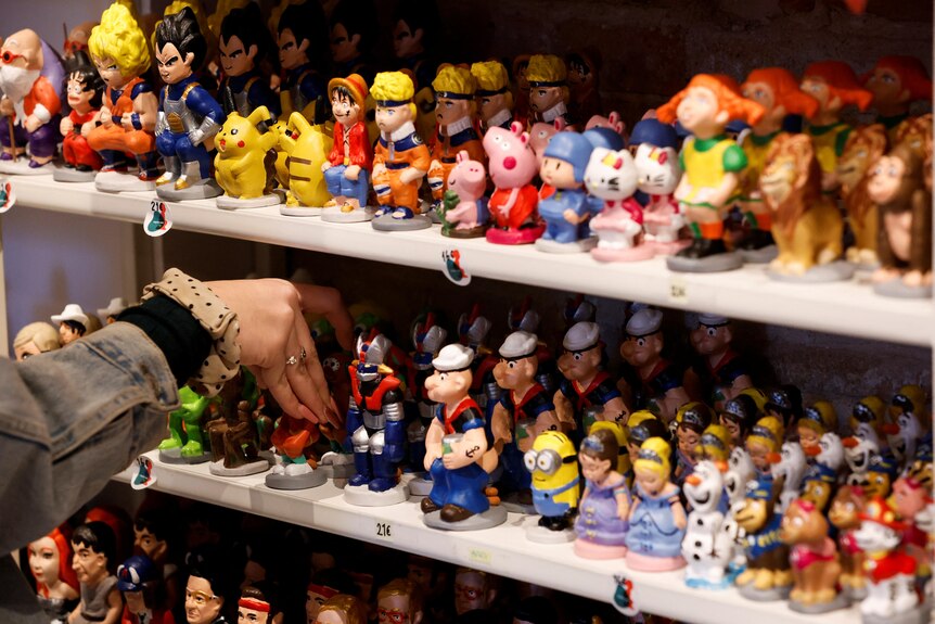 A row of small, squatting figures of a range of pop culture characters from comics, animated shows and movies.