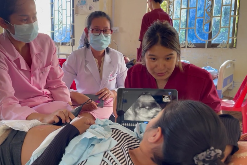 Three healthcare workers doing ultrasound with a pregnant woman.