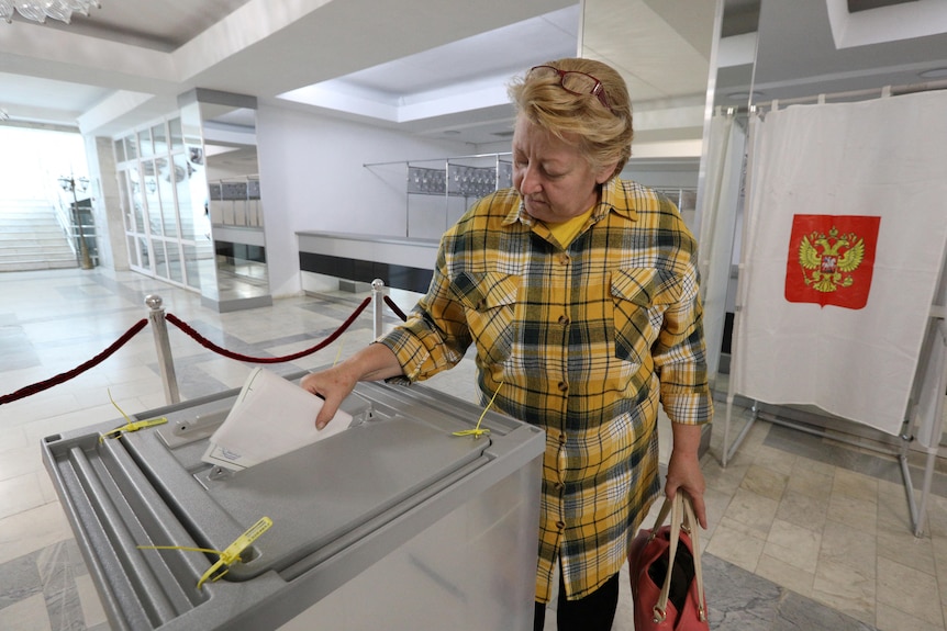 A woman casts her vote in a ballot box during a referendum
