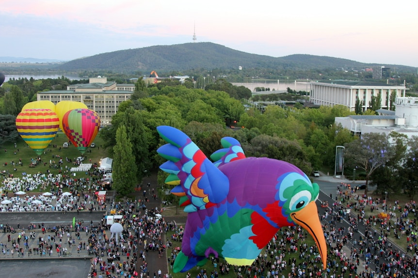 Hummingbird hot air balloon prepares for take off amid surrounding crowds.
