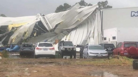 A building damaged by a tornado, cars parked outside