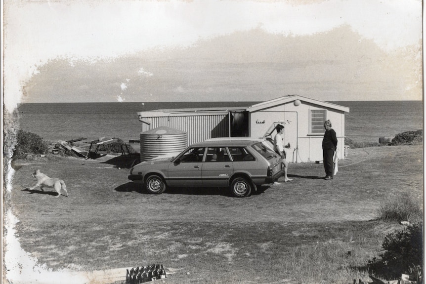 An old historic photo of Mike Agnew chatting with his dad in front of a shack