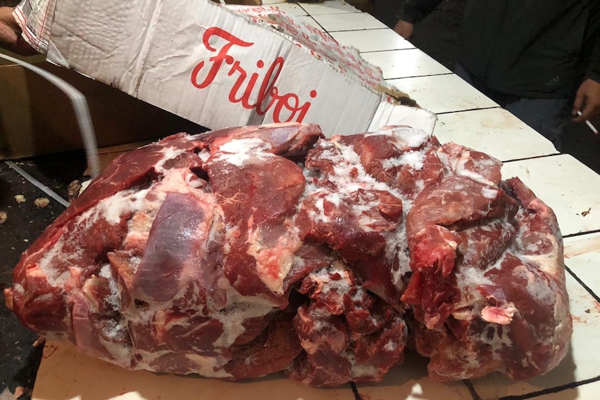A block of frozen beef pieces sits on a tiled surface