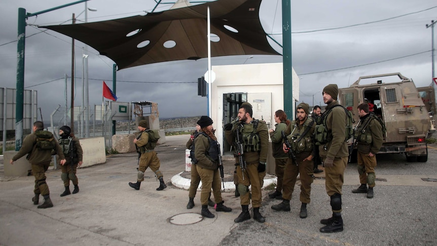 Israeli soldiers stand guard at a checkpoint near a West Bank settlement.