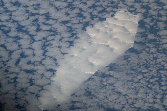 A white iceberg in almost straight edges with an outline that looks like a coffin. The berg is obscured by heavy cloud cover.