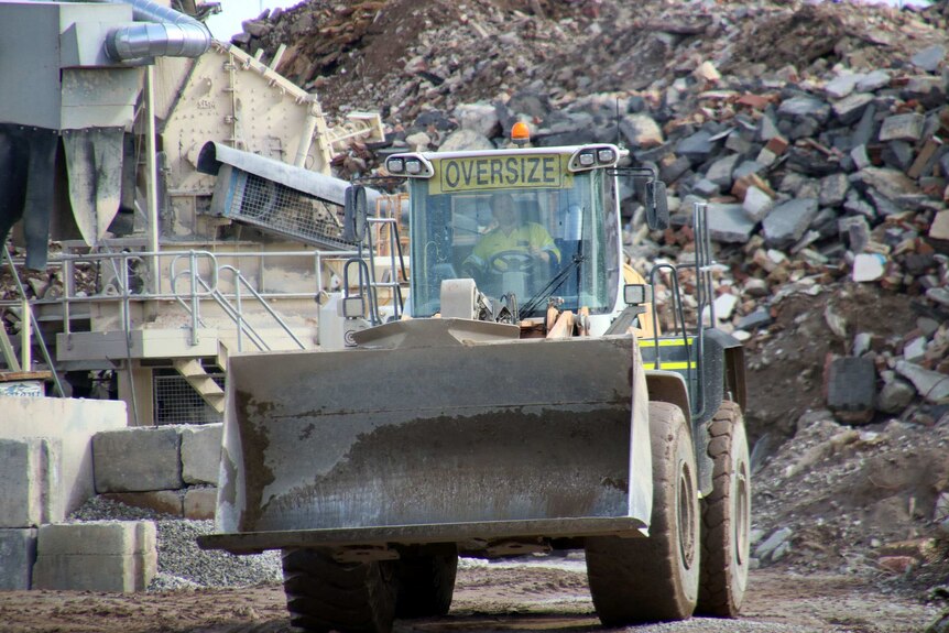 A worker drives a bulldozer at the Resource Recovery Solutions Bayswater recycling facility.