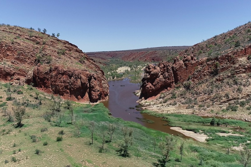 Acantilados rocosos rojizos a ambos lados del agua oscura que fluye cuesta abajo