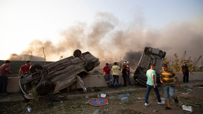 Overturned cars and smoke amidst debris following an explosion in Beirut.
