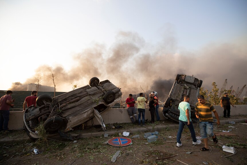 Overturned cars and smoke amidst debris following an explosion in Beirut.