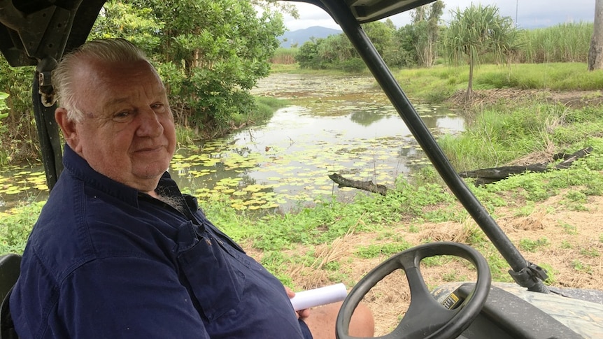 An older cane farmer looks from his All Terrain Vehicle across a lagoon which is designed to minimise farm run-off