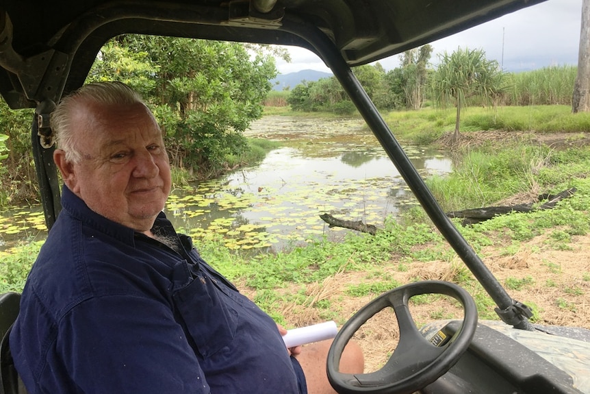 An older cane farmer looks from his All Terrain Vehicle across a lagoon which is designed to minimise farm run-off