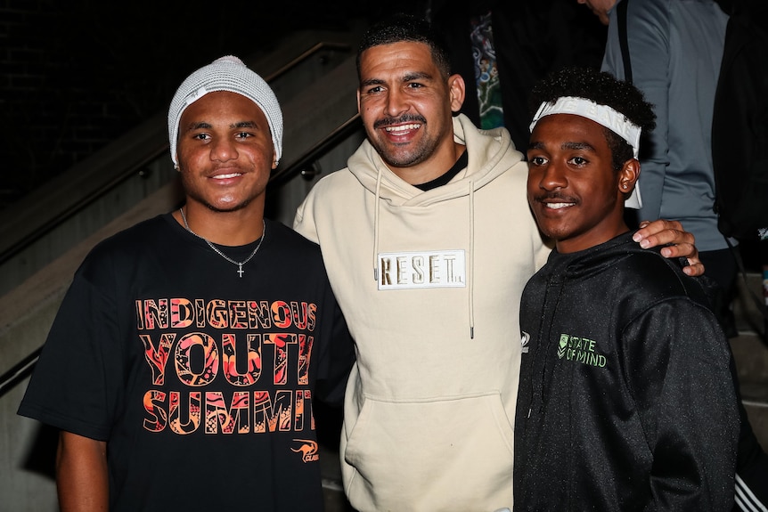 Trois hommes debout côte à côte, souriant pour une photo