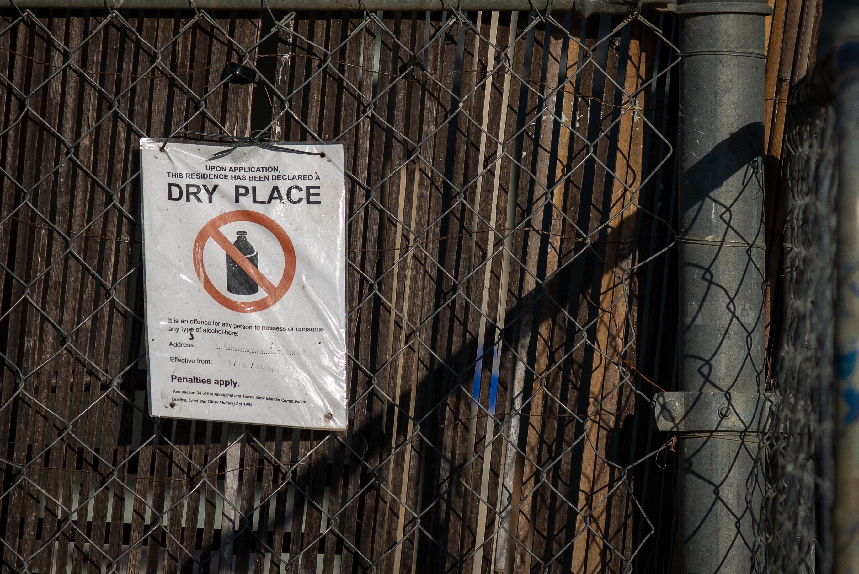 A laminated sign hangs from a fence warning people not to bring alcohol on a premises in Kowanyama.