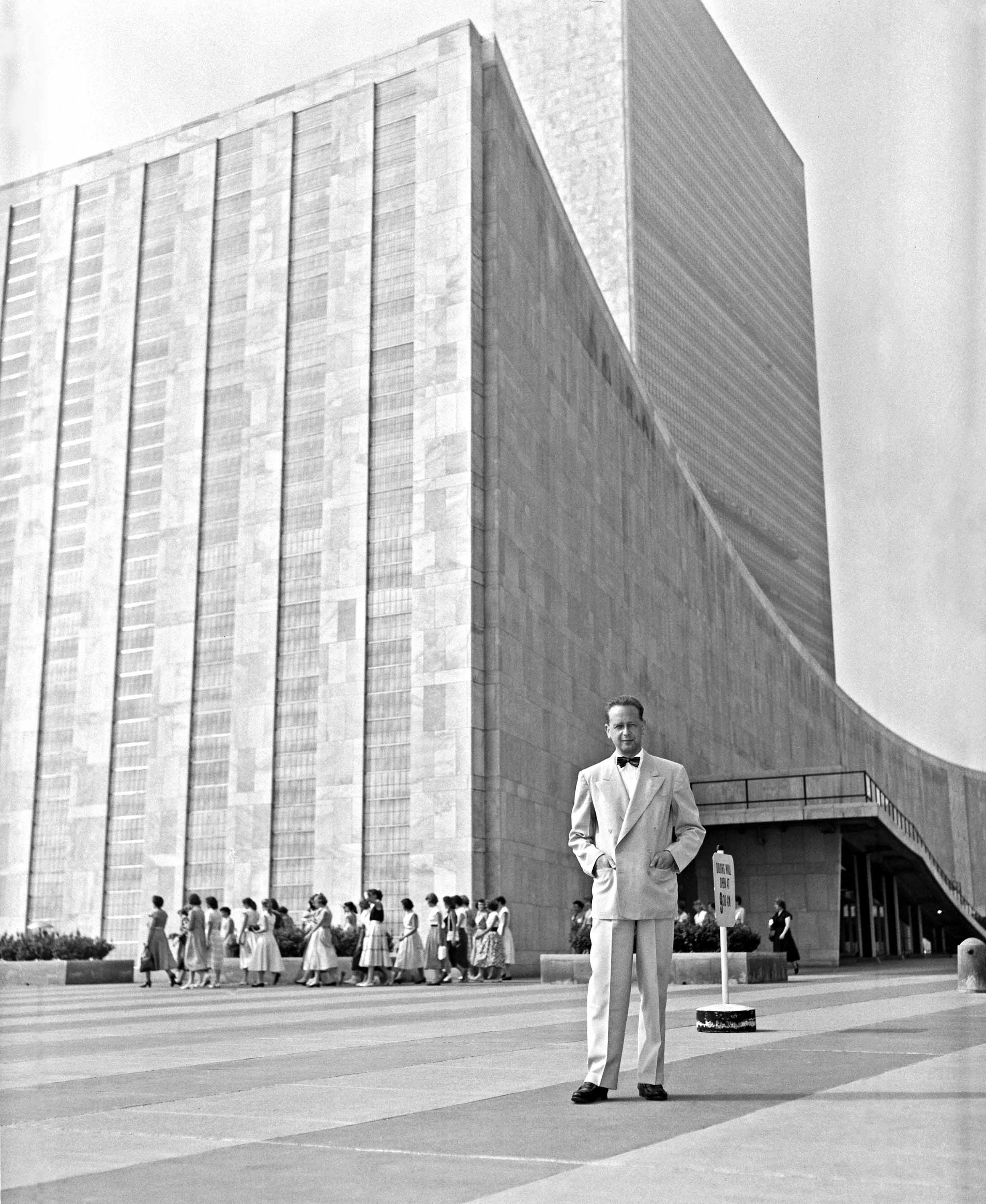 A black and white photo of Dag Hammarskjold posing outside the UN building