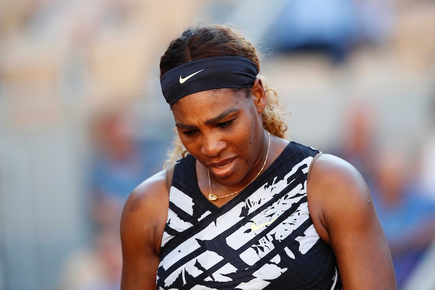 A tennis player walks back with her head down after losing a point.