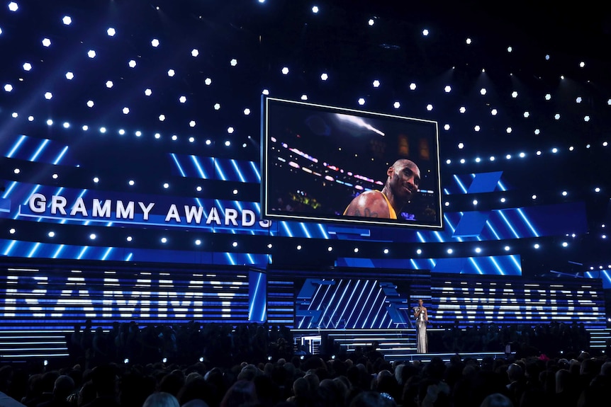 Alicia Keys speaks on stage at the Grammys with a picture of Kobe Bryant in the background