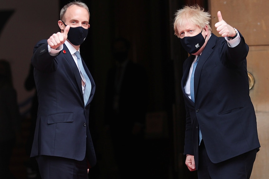 Dominic Raab and Boris Johnson gesture with thumbs up towards the camera while wearing masks.
