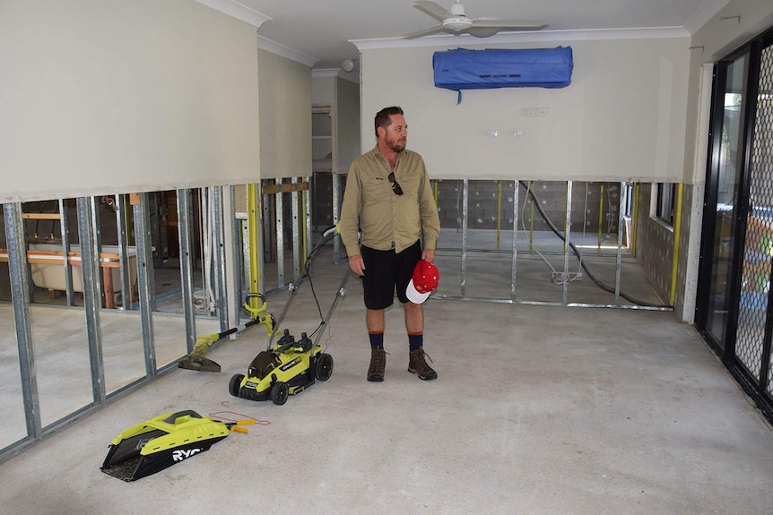 A man standing in the bottom of a house with walls stripped bare