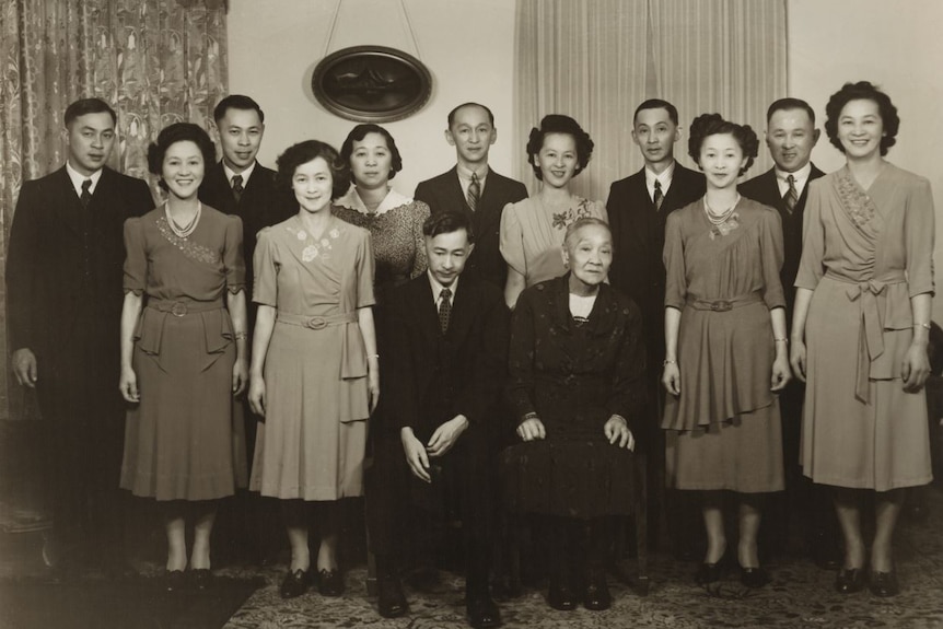 A large family portrait in black and white of an Asian family in the early 20th century.