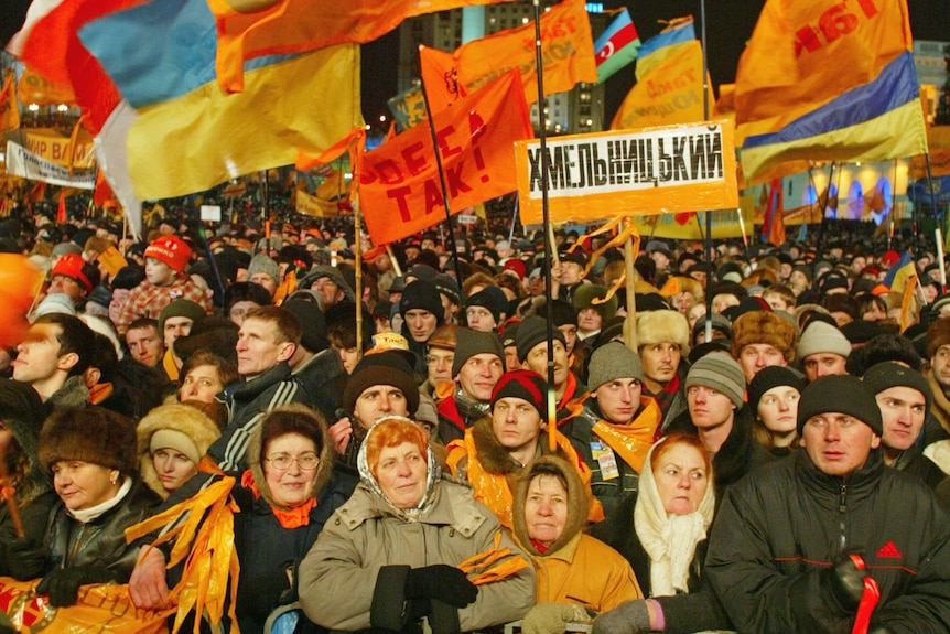 a group of supporters of Viktor Yushchenko gather in central Kyiv, holding flags and wearing orange colours