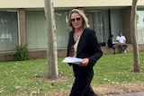 Blonde woman in black blazer and pants leaving courthouse