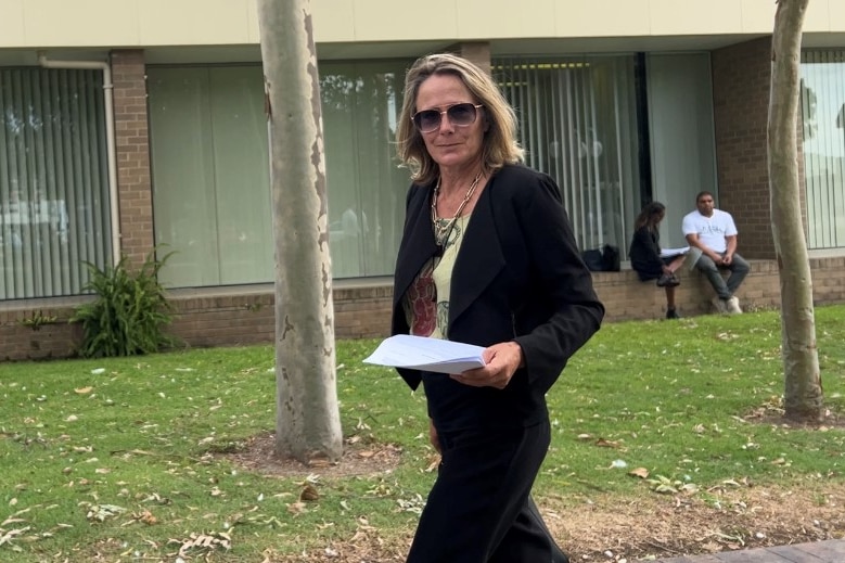 Blonde woman in black blazer and pants leaving courthouse
