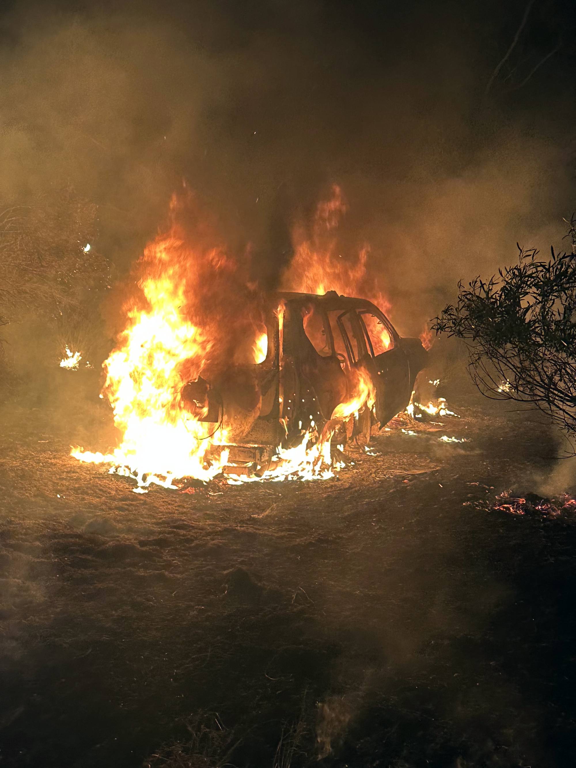 A car is engulfed in flames in the bush.