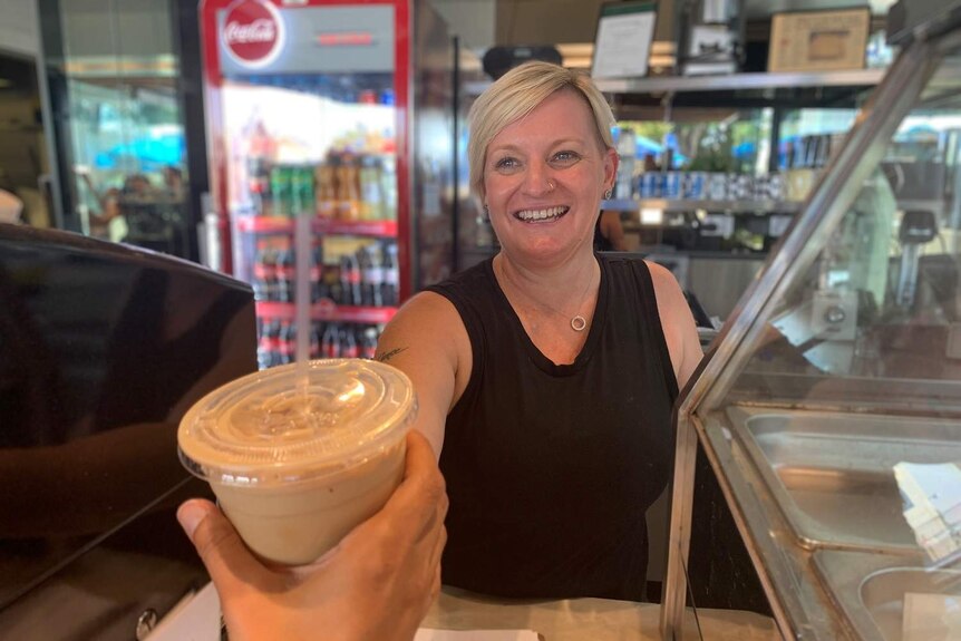 Ms Norton hands an iced latte to a customer.